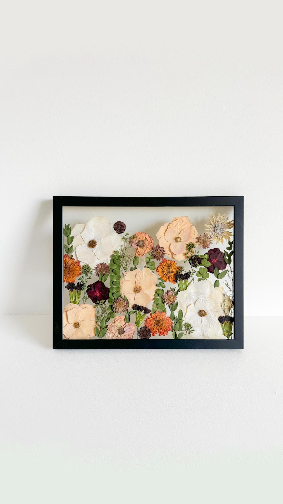 black frame with a pressed floral arrangement